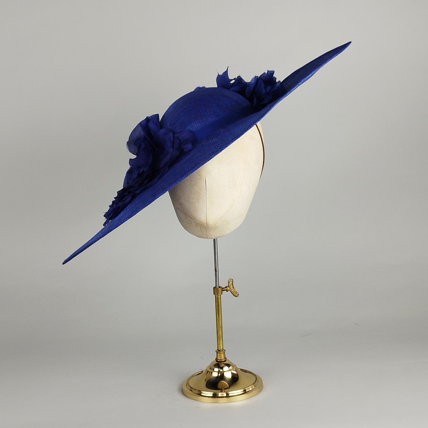 Royal blue hat with large silk flowers, offering a stunning look for weddings and Royal Ascot.