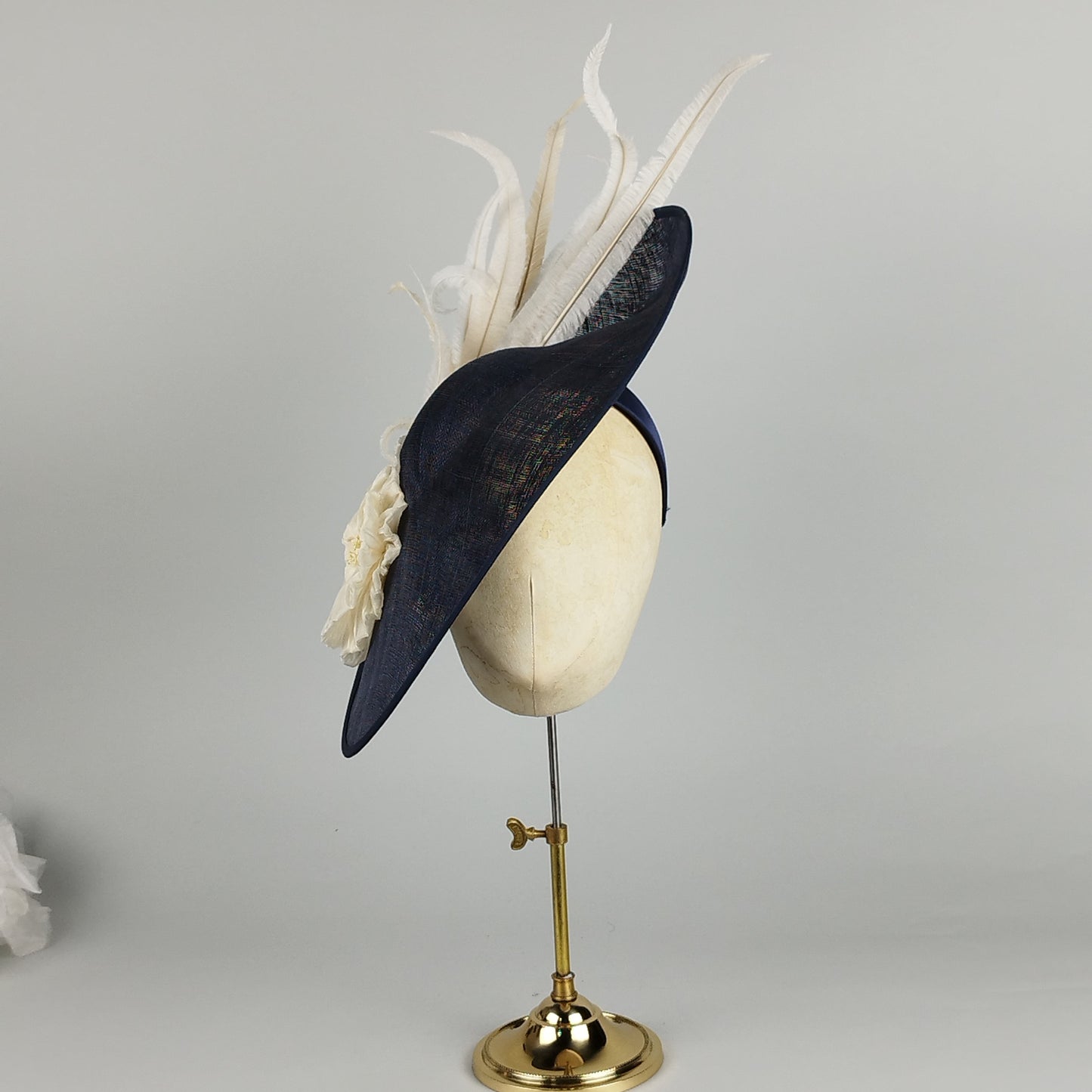 Navy hatinator with ivory pleated flower and twirling ostrich feathers, perfect for weddings and Royal Ascot.