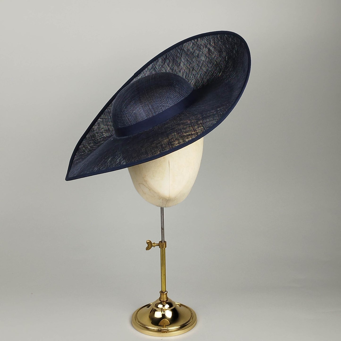 Navy hat for hire with dramatic upturned design. Perfect Navy wedding hat combining architectural elements with contemporary British millinery. Customizable for personal style.