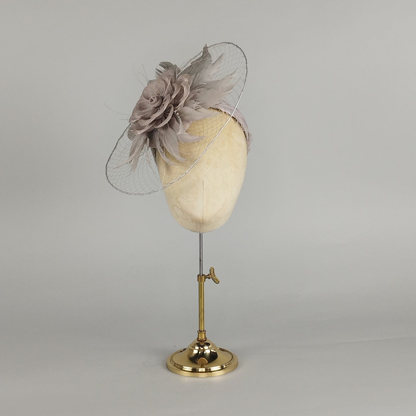 Silver fascinator with veiled brim and feather detail