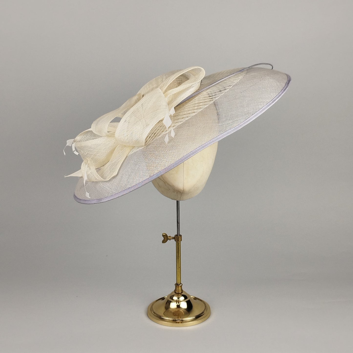 Grey and cream hatinator with bow and feathers. Fascinator for hire.