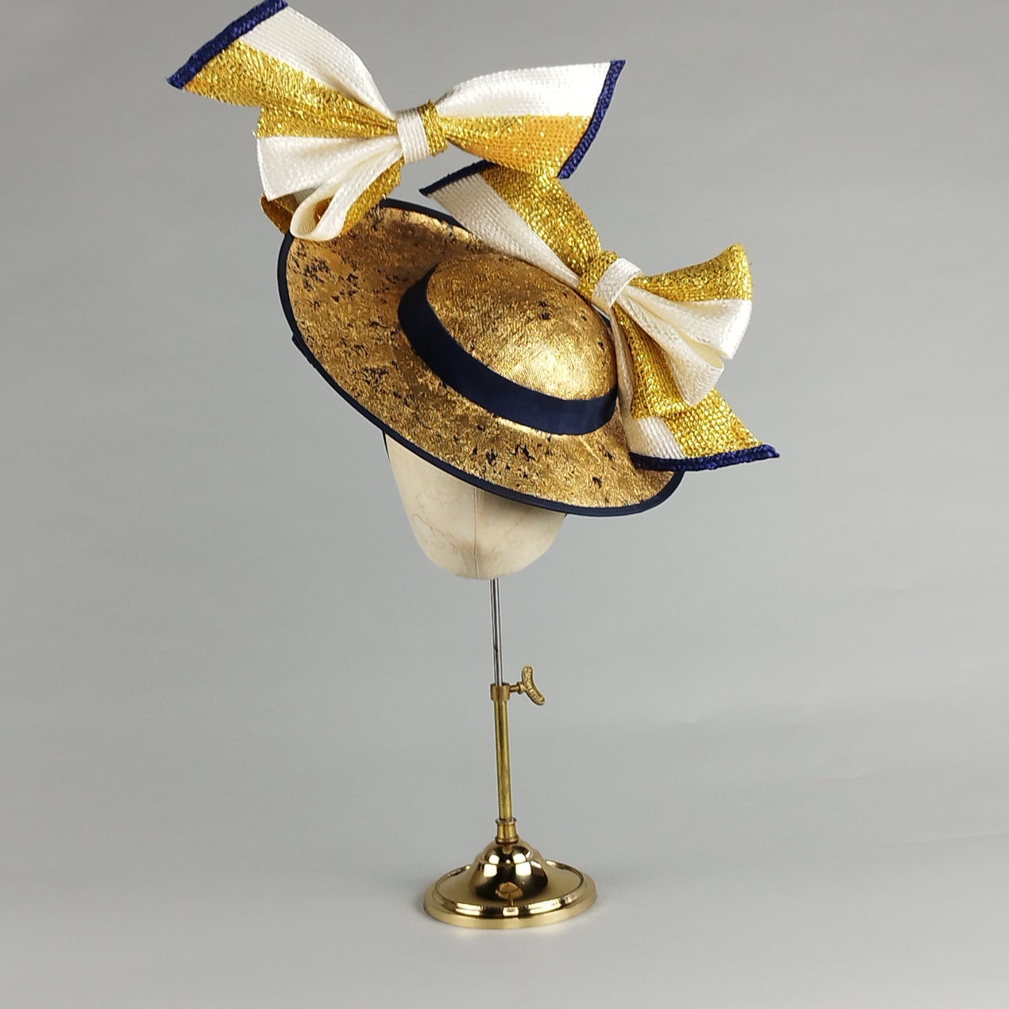 Navy and gold fascinator with oversized bows, distressed gold leaf, and contemporary millinery flair. Perfect for Royal Ascot or weddings.