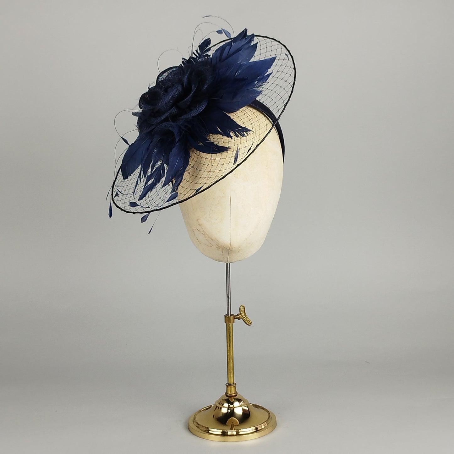 Navy fascinator with sinamay rose, feathers, and structured veil, perfect for weddings and Royal Ascot.