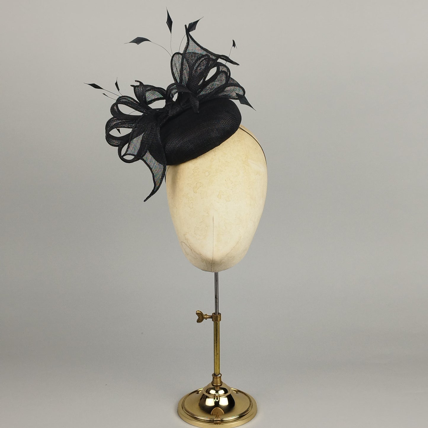 Black pillbox hat with sculptural bow and dramatic feather detail