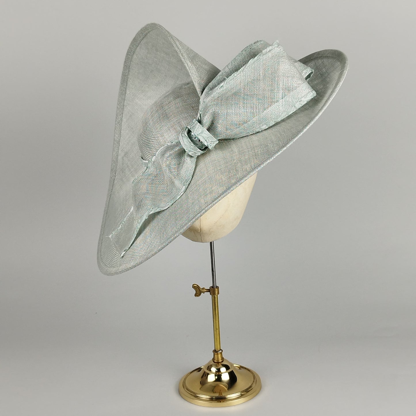 Pistachio green hat with twisted brim and front bow – modern elegance with a twist.