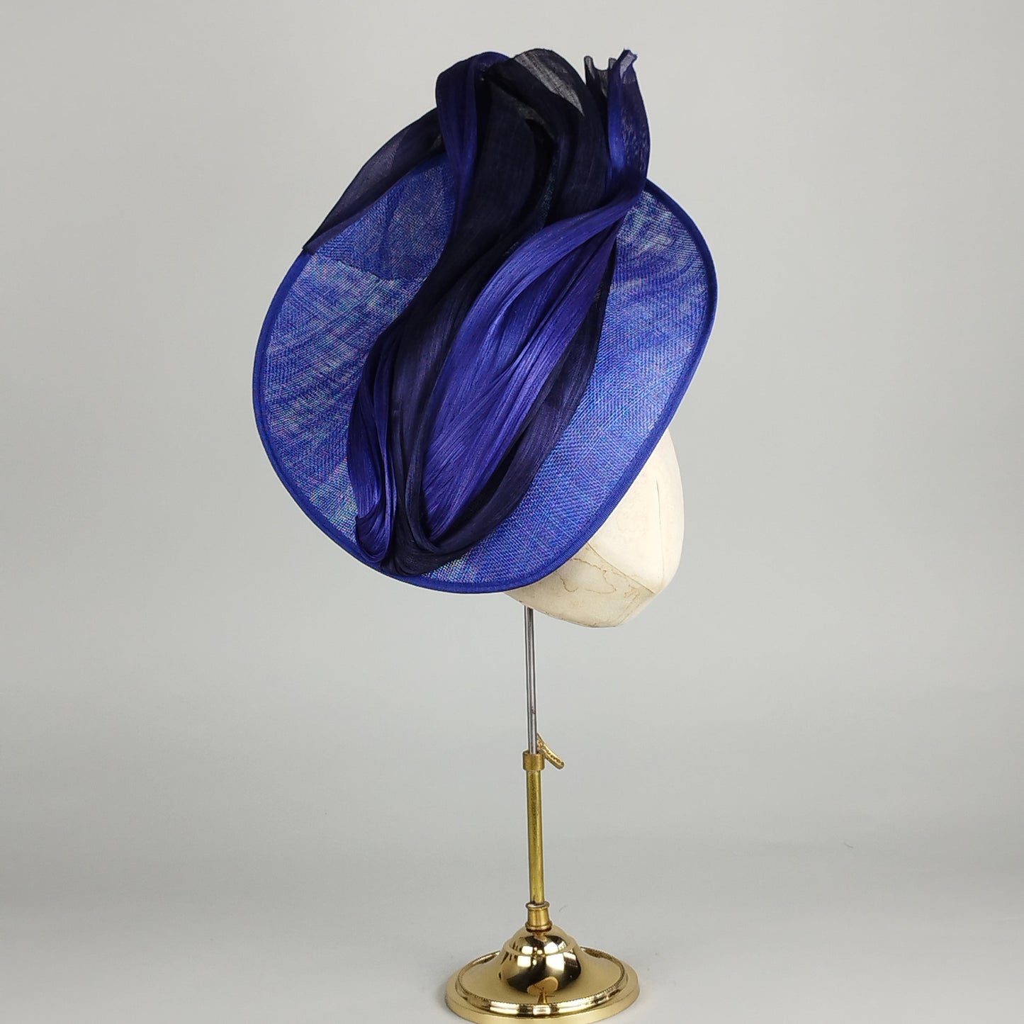 Royal blue fascinator with silk abaca in varying blues, featuring a cool upsweep and cutaway face design, ideal for weddings and Royal Ascot.