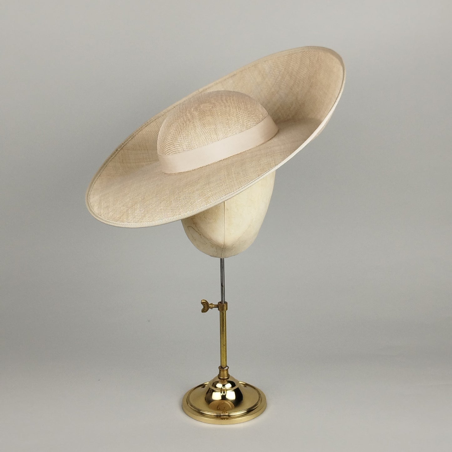 Champagne sculptural hat with dramatic sloped crown and upturned brim