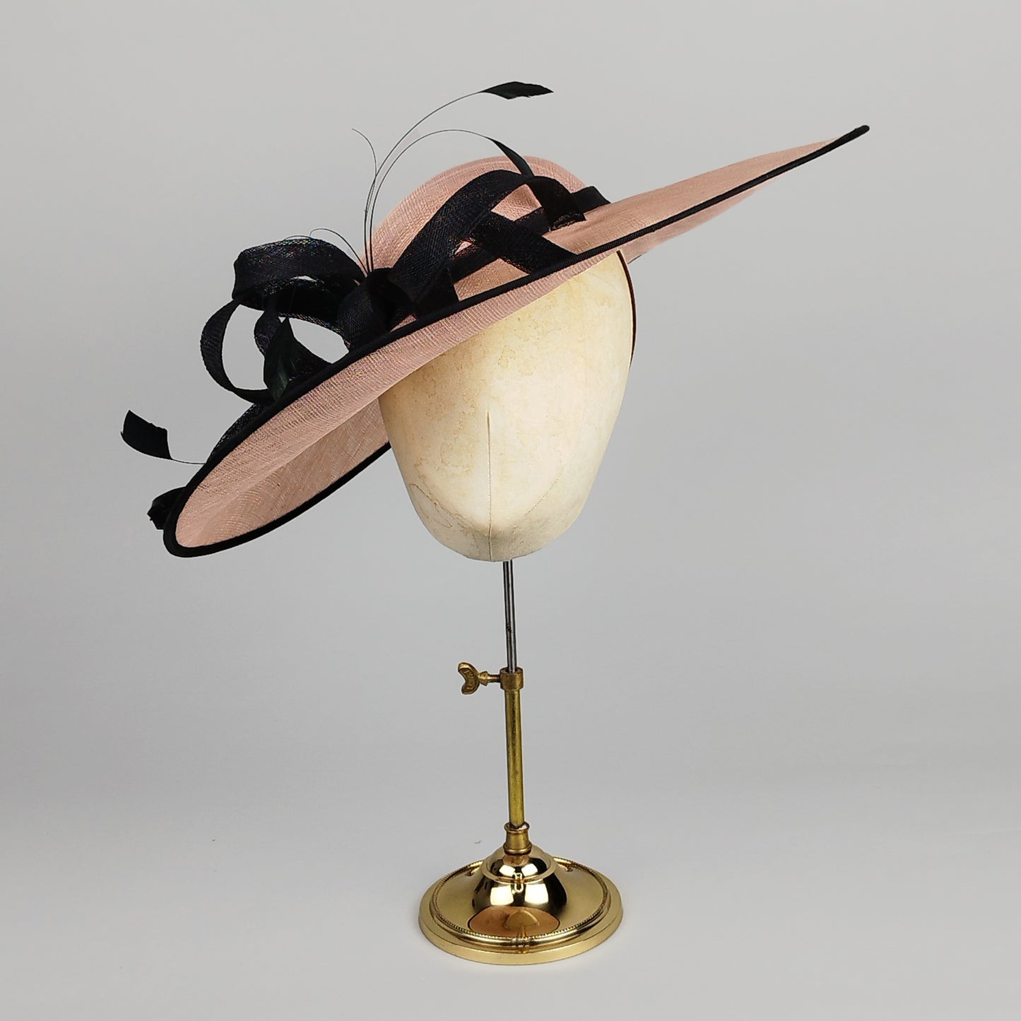 Pale pink and black hatinator with loops, swirls, and feathers – chic and bold
