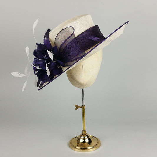 Formal purple and cream feathered wedding hat with a large flower and bow.