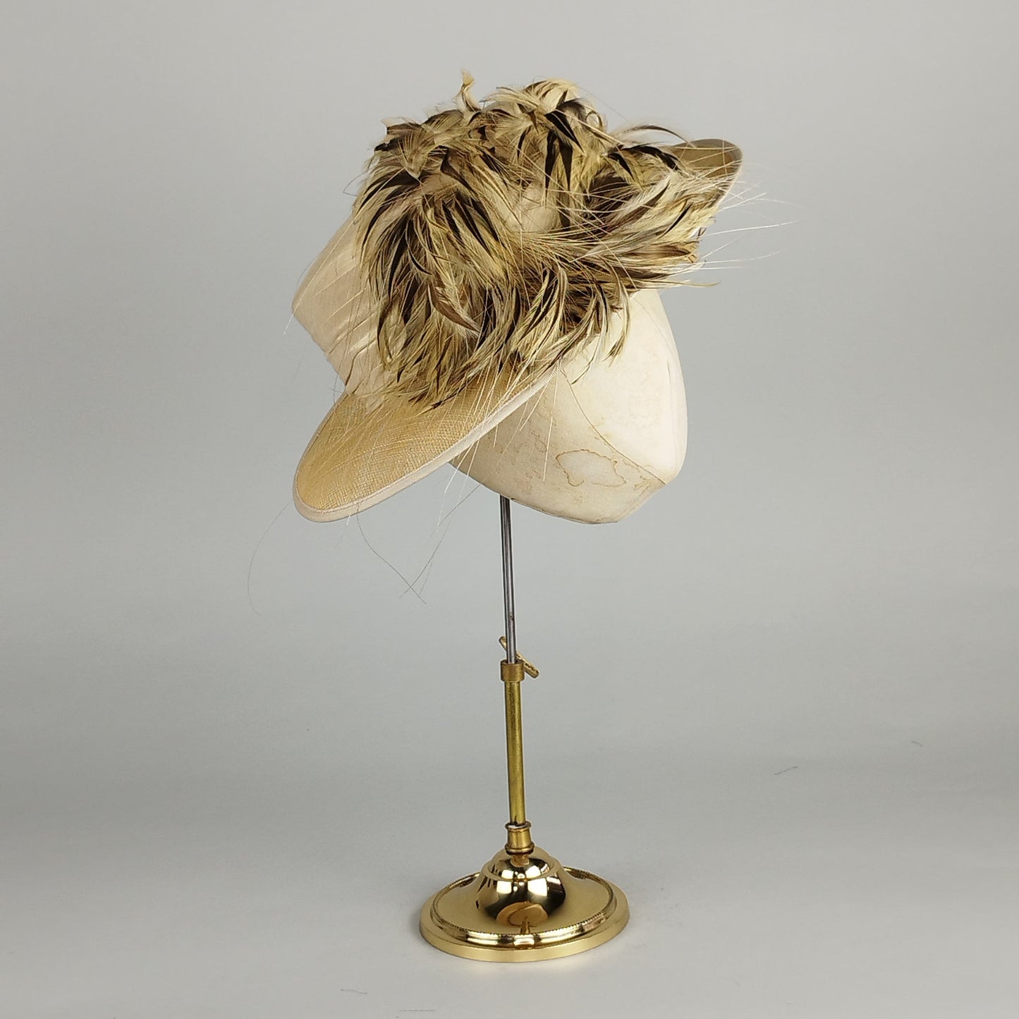 Neutral cream ladies formal hat with silk band and lively feather accent in brown, beige, and cream for weddings or Royal Ascot.