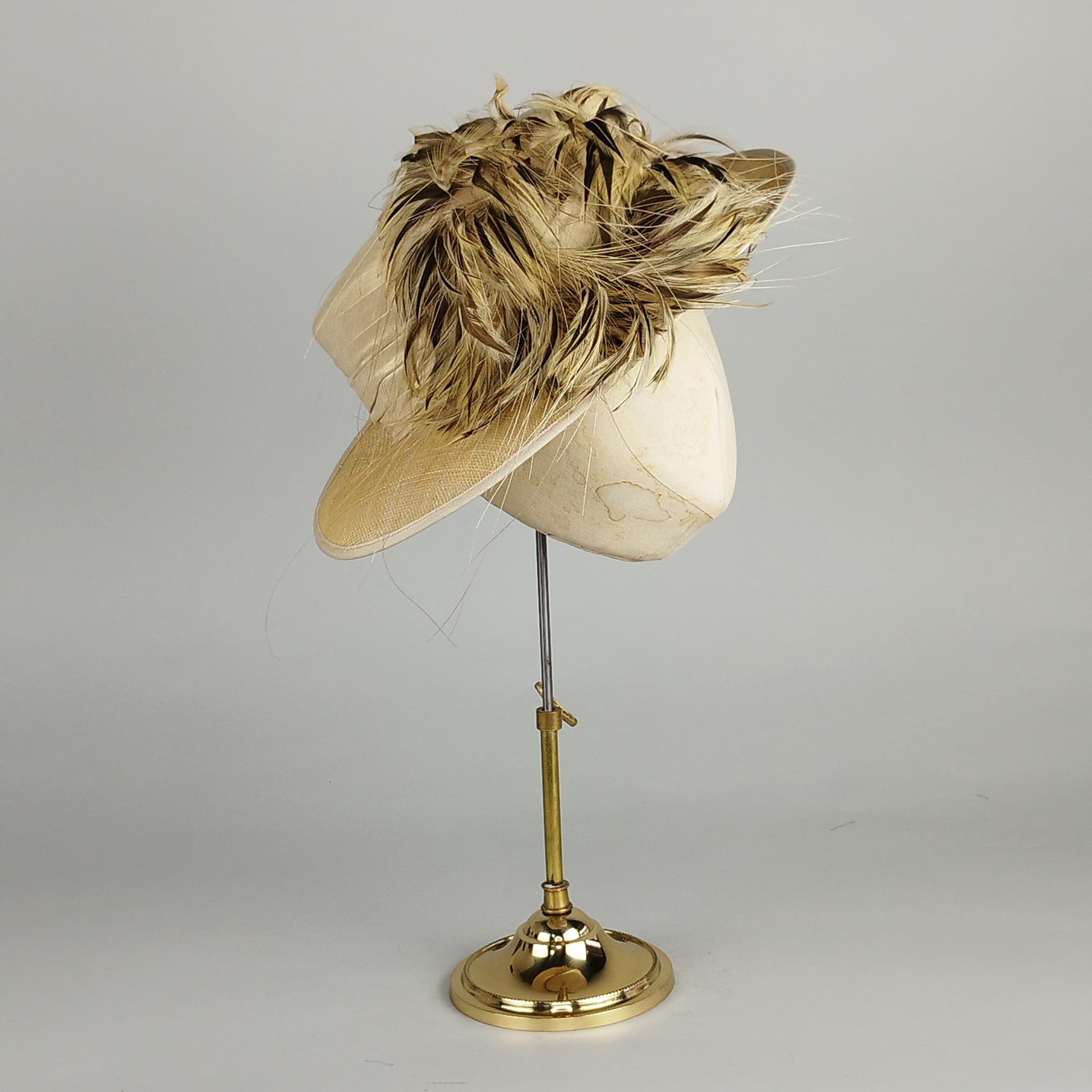 Neutral cream ladies formal hat with silk band and lively feather accent in brown, beige, and cream for weddings or Royal Ascot.