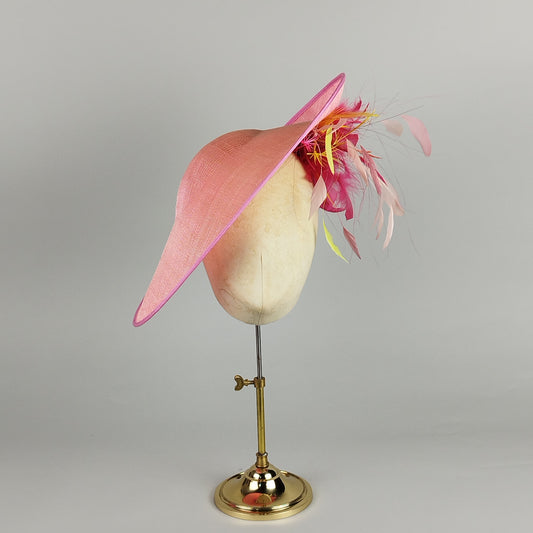 Hot pink hatinator with neon multicoloured feather spray, bold and playful.