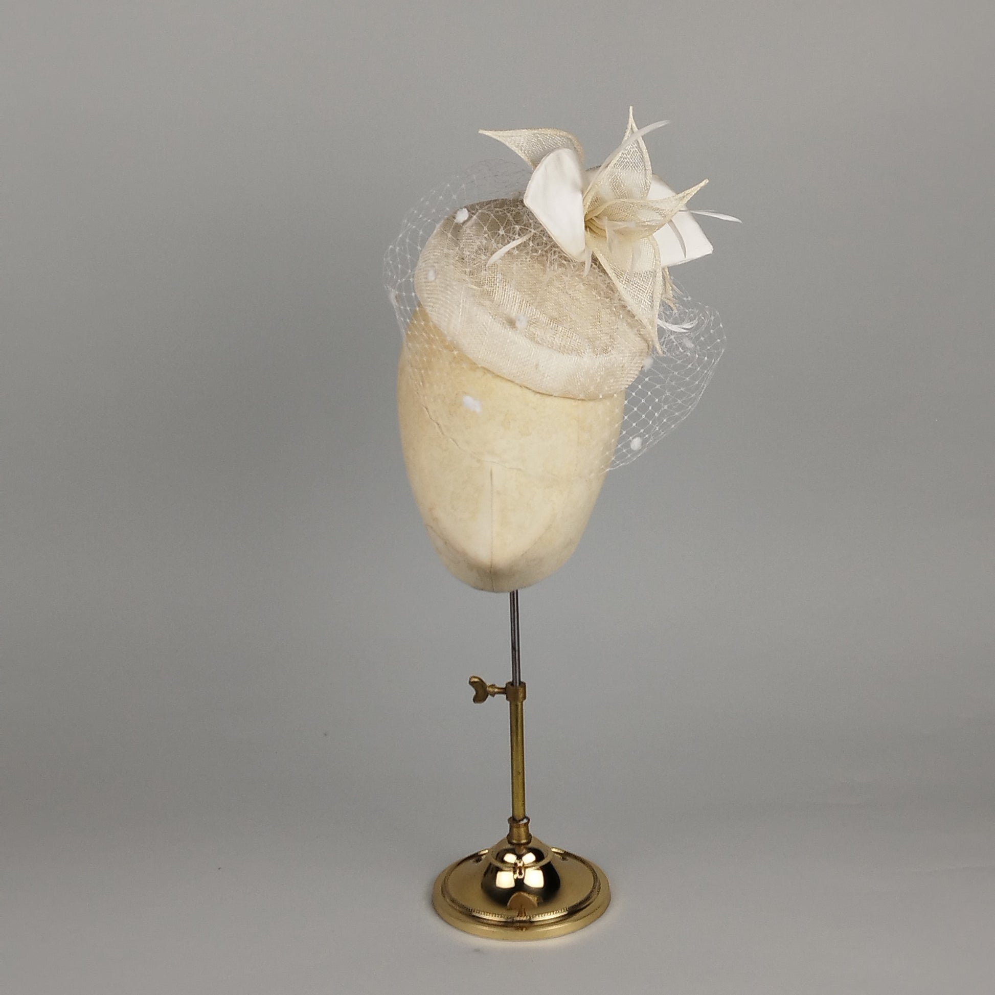 Ivory pillbox hat with birdcage veil and sculptural flower detail