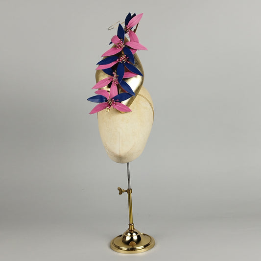 Gold leather fascinator with pink and blue flowers and twisted quill, perfect for Royal Ascot or bold events.