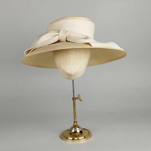 Neutral cream straw hat with large fabric bow, perfect for Royal Ascot, garden parties, and casual outings.