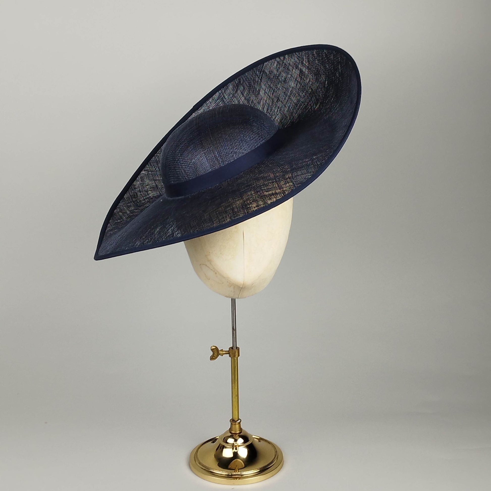 Navy hat for hire with dramatic upturned design. Perfect Navy wedding hat combining architectural elements with contemporary British millinery. Customizable for personal style.