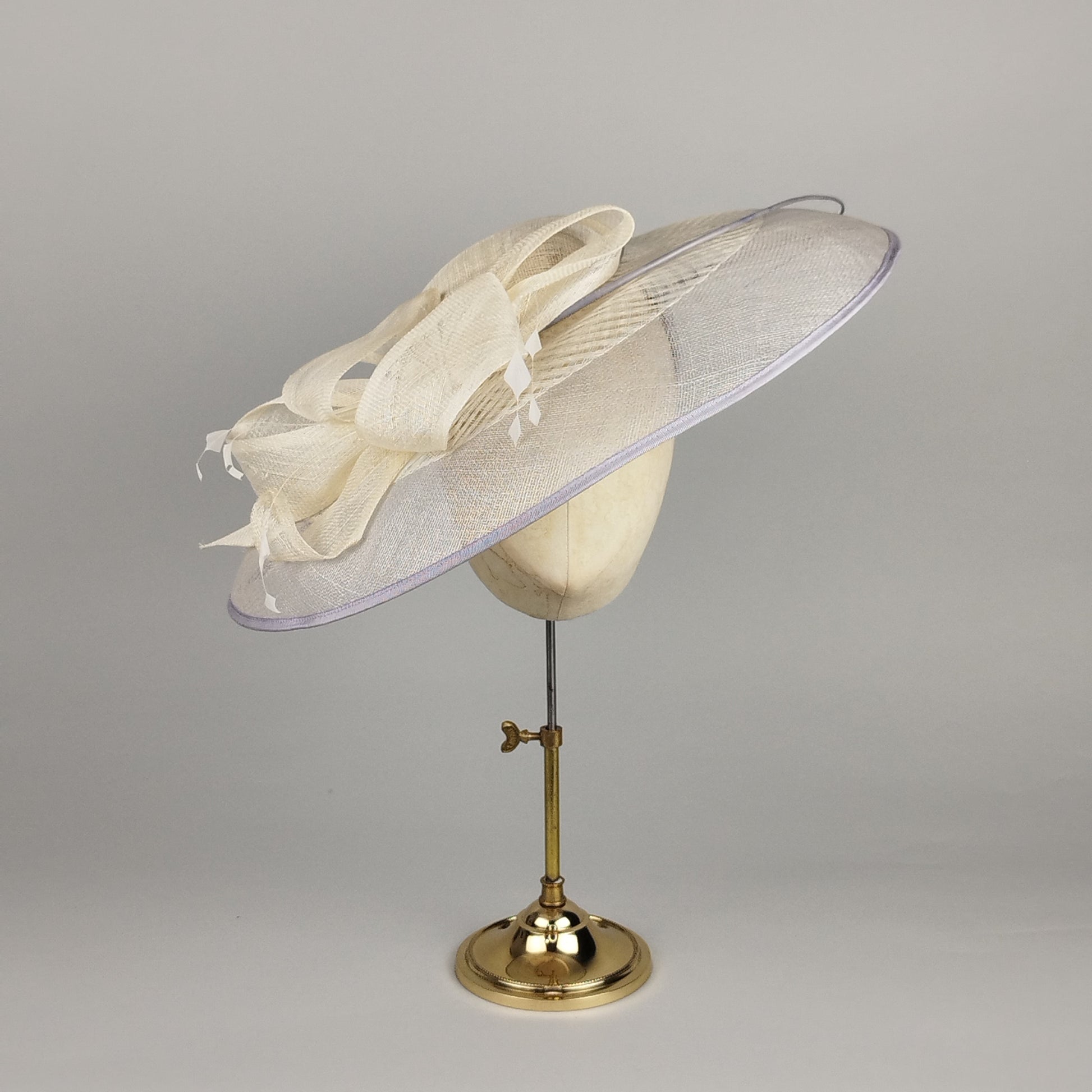Grey and cream hatinator with bow and feathers. Fascinator for hire.