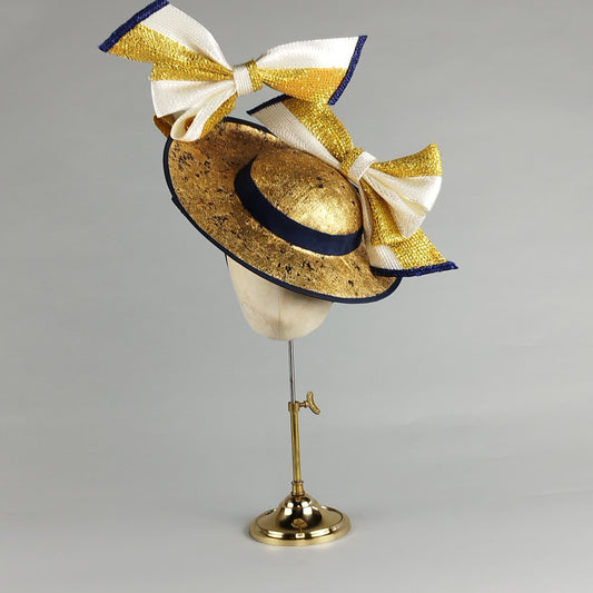 Navy and gold fascinator with oversized bows, distressed gold leaf, and contemporary millinery flair. Perfect for Royal Ascot or weddings.