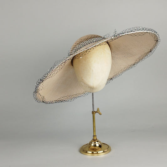 Neutral wide-brimmed hat with black netting and pearls, perfect for weddings, Royal Ascot, or special occasions.