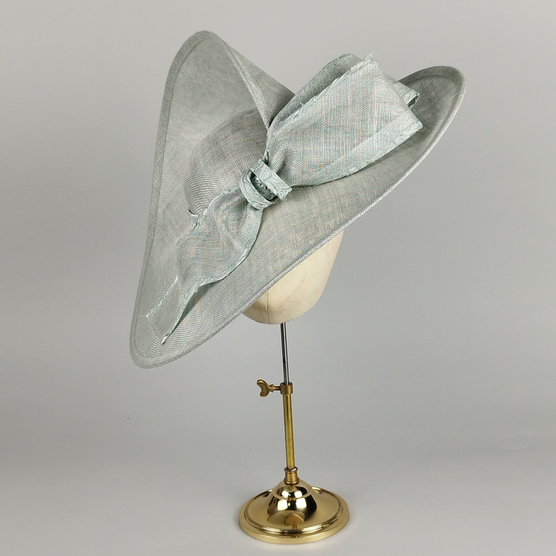 Pistachio green hat with twisted brim and front bow – modern elegance with a twist.