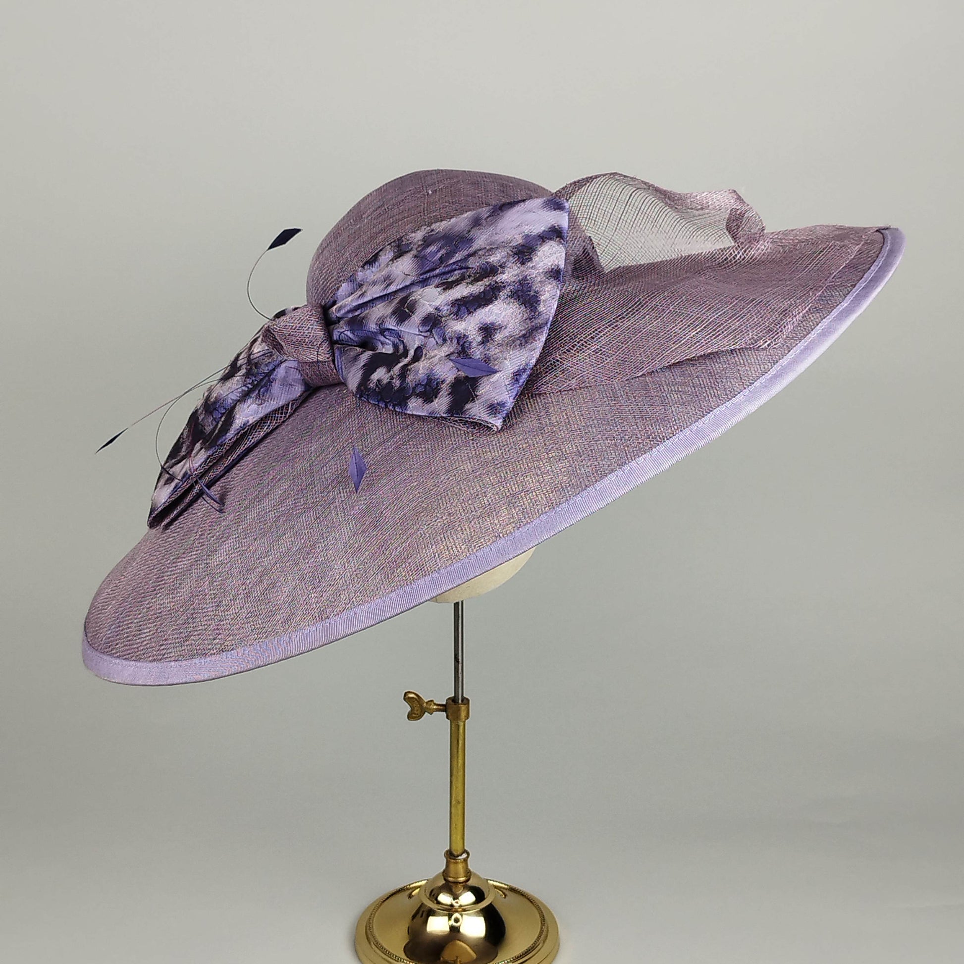 Purple wide-brim hat with bow decoration, perfect for weddings, Royal Ascot, and race days.