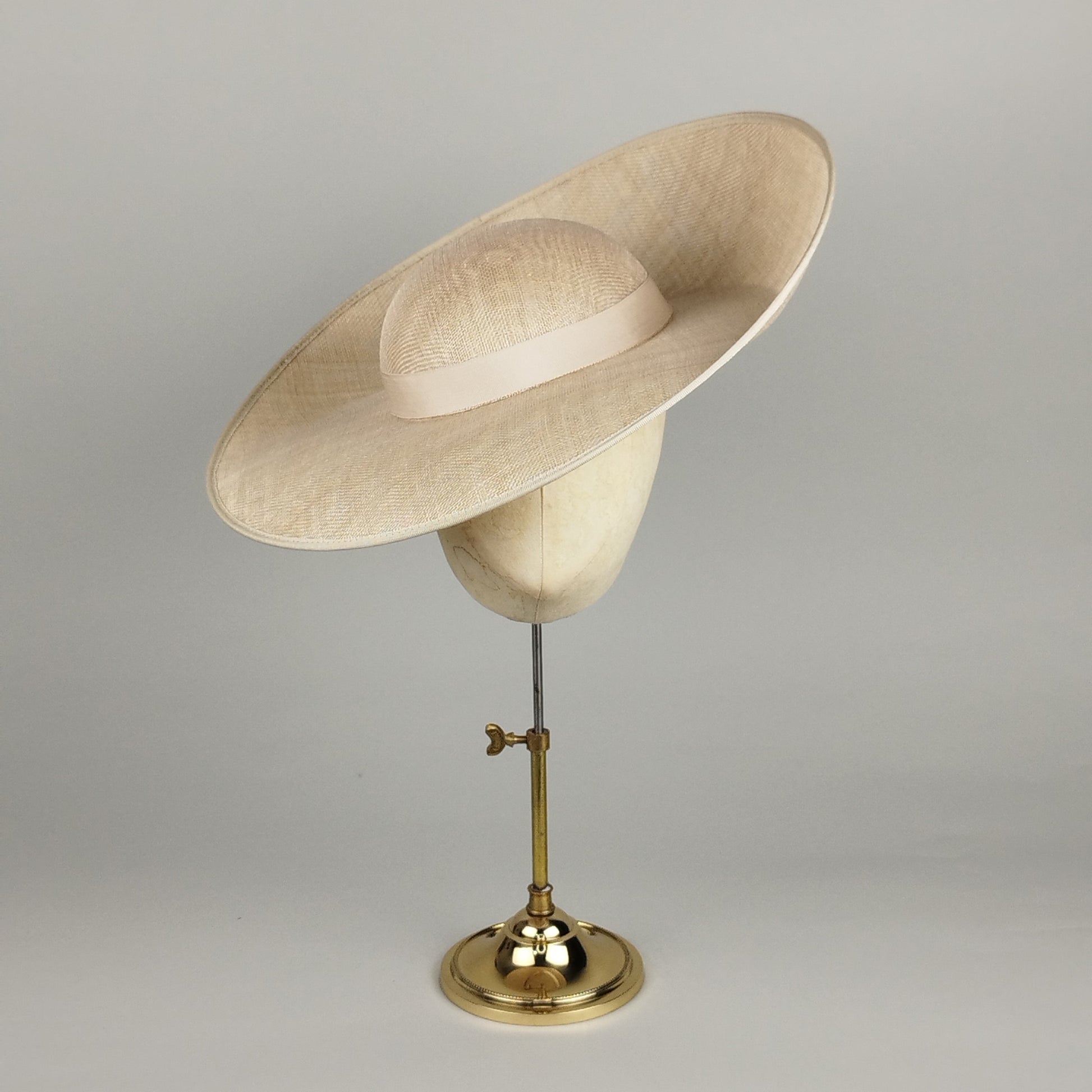 Champagne sculptural hat with dramatic sloped crown and upturned brim